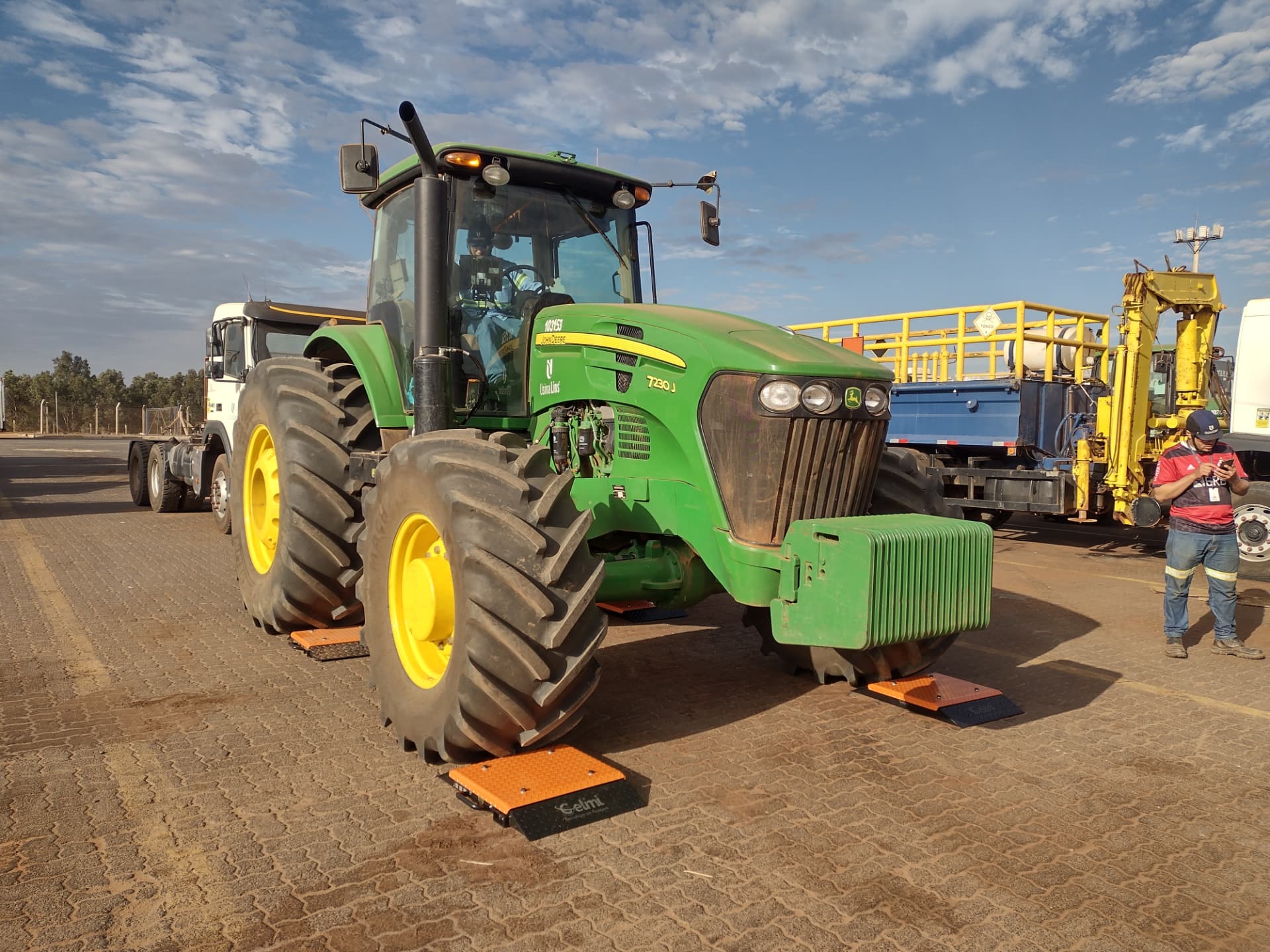 Trator agrícola posicionado sobre balanças portáteis CELMI CM-1002 para pesagem por roda